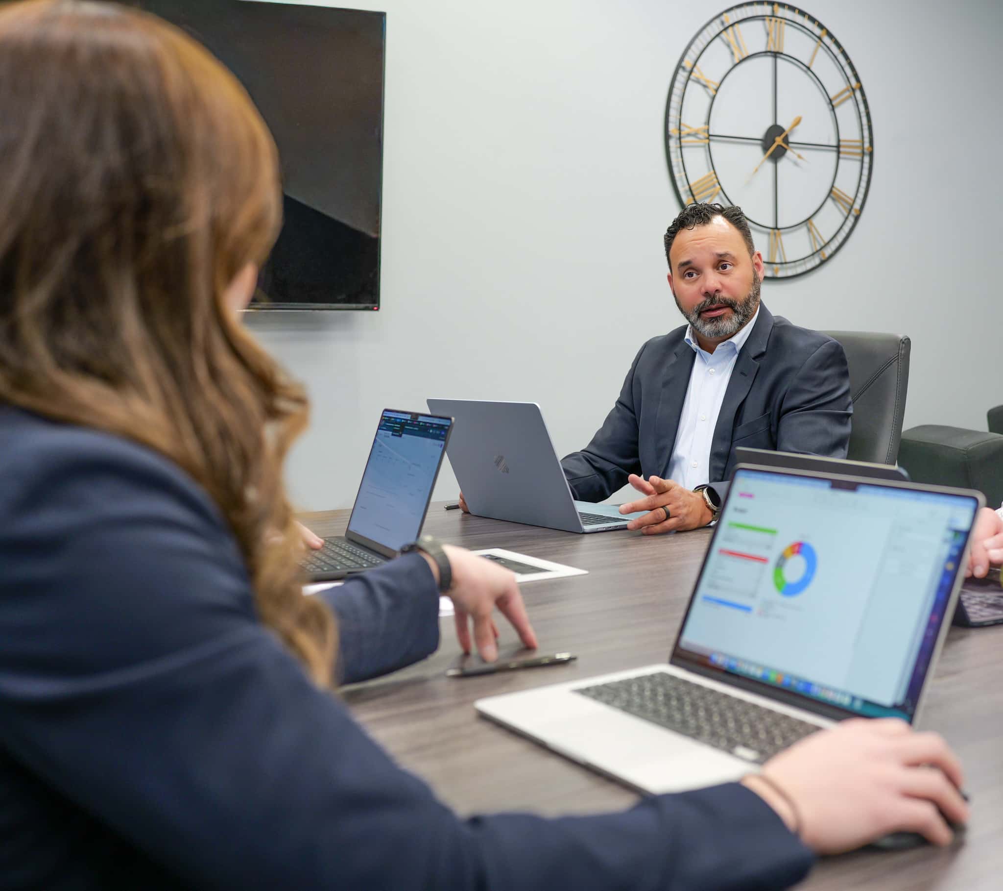 Presenter pointing at screen with data on it infront of a team.